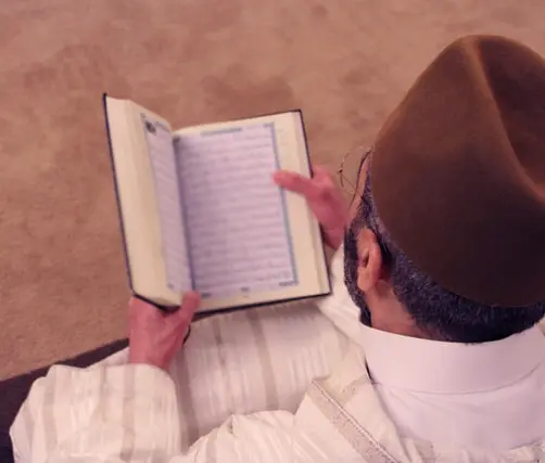 صورة تحتوي على شخص يحمل كتاباً شيخ روحاني في الدمام