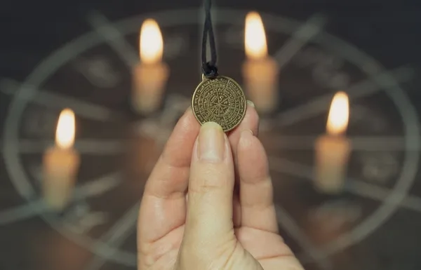 صورة تحتوي على يد تمسك قلادة وشموع رقم ساحر مجرب